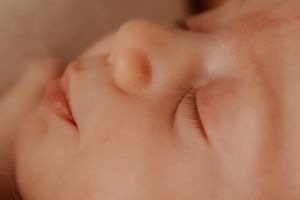 Extreme close-up detail of soft newborn features in gentle lighting.