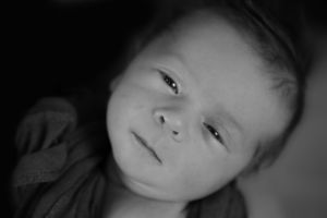 Black and white close-up newborn portrait in gentle lighting.