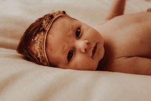 Intimate sepia portrait of a baby wearing a crown in natural lighting.