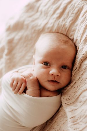Close-up series of baby wrapped in white blanket showing different peaceful expressions.