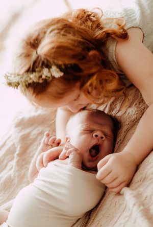 Series of gentle close-up moments between parent and baby on white bedding.