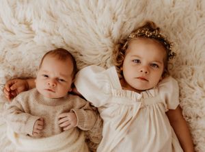 Baby in cream-colored clothing lying on plush textured blanket in various poses.