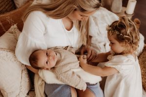 Intimate newborn photography session showing gentle embraces in soft lighting.