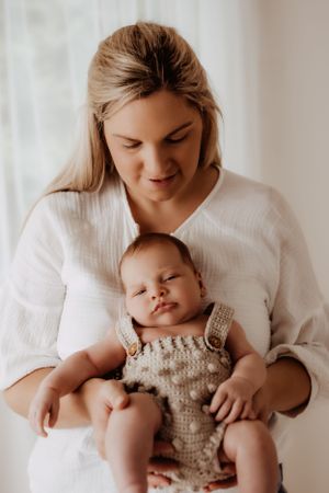 Parent holding baby wearing knitted romper in series of tender moments against white background.