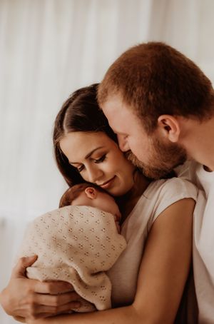 Tender family moment captured in warm tones against white backdrop.