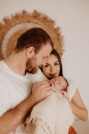 Intimate family moment captured on white bedding with warm lighting.