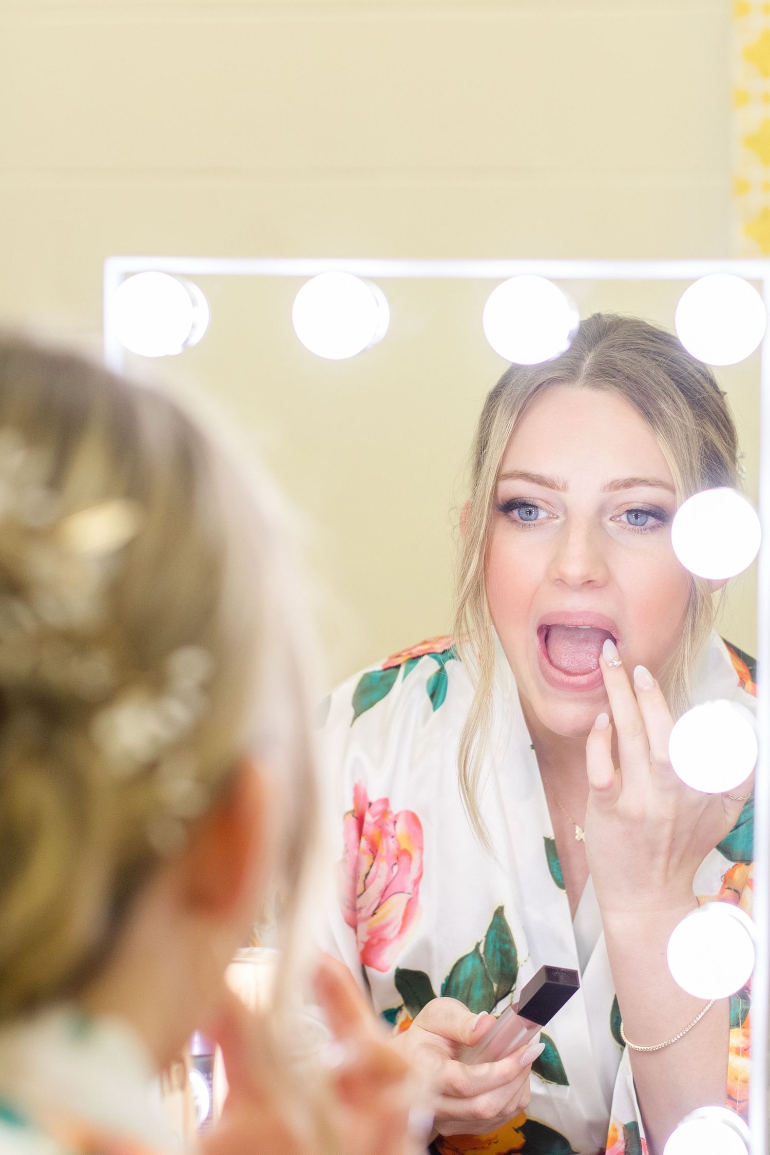 Getting ready scene with vanity lights and floral robes reflected in mirror.