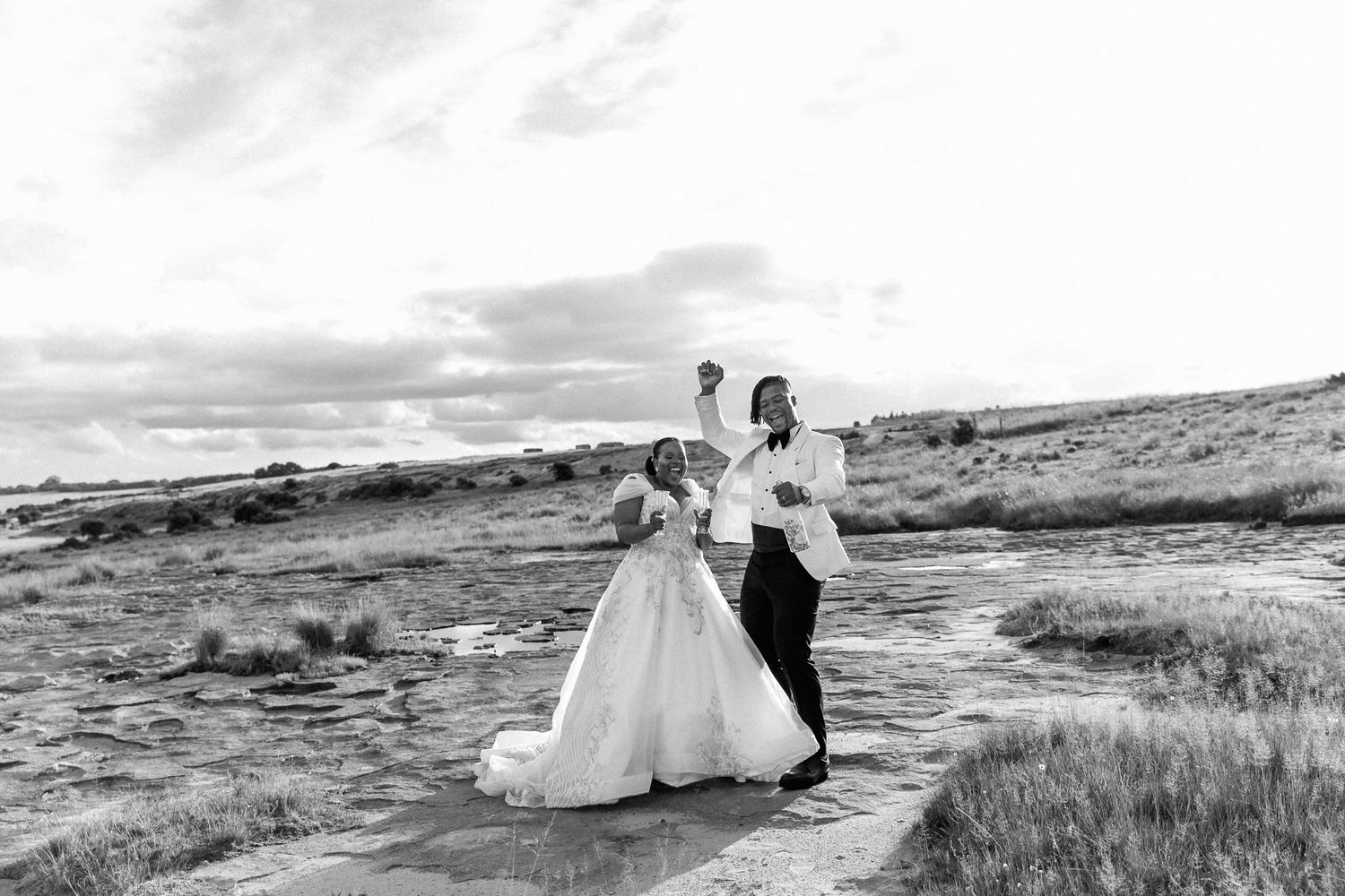 Sunset champagne toast at Florence Wedding Venue. Howard & Gugu show off their wedding attire on a rocky hill.