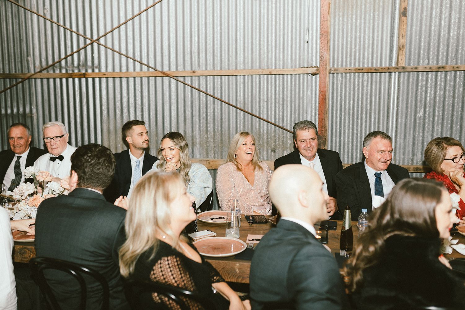 Wedding guests enjoying dinner at rustic reception venue with industrial design elements.