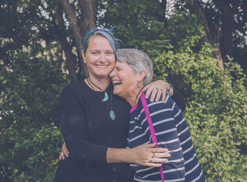 Two people sharing a warm embrace outdoors with joyful laughter.