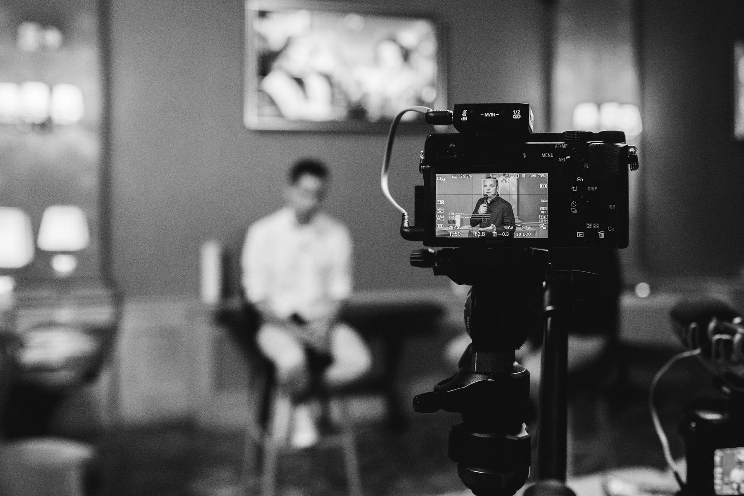 Professional camera setup showing interview framing on LCD screen.