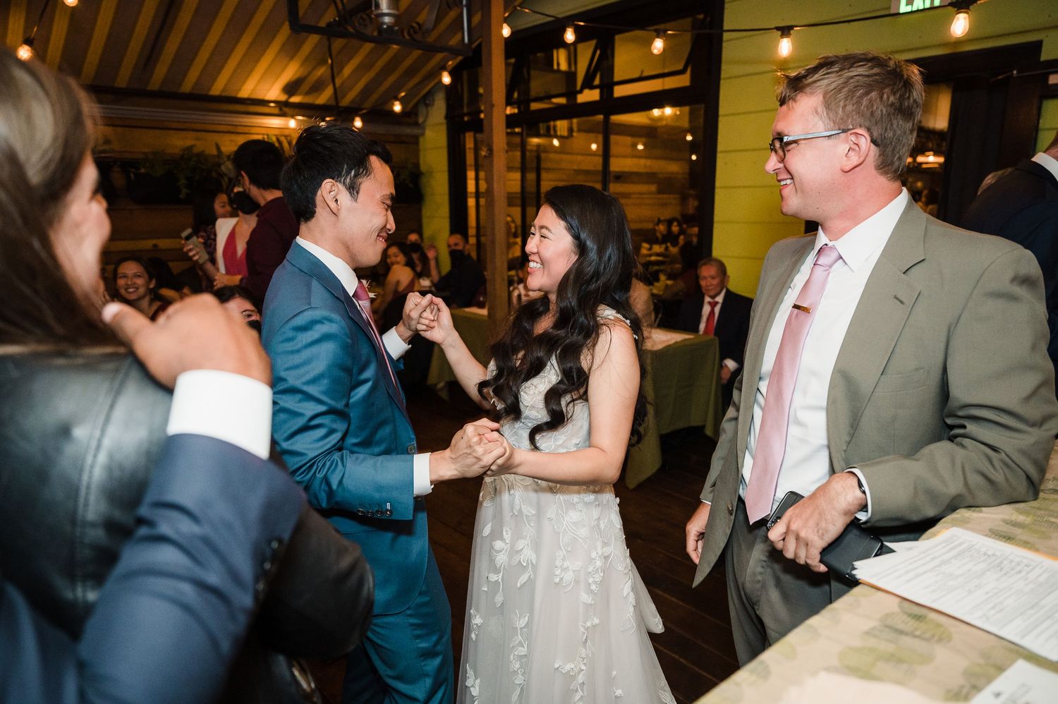 Guests mingle and celebrate at an indoor reception with wooden ceiling beams.