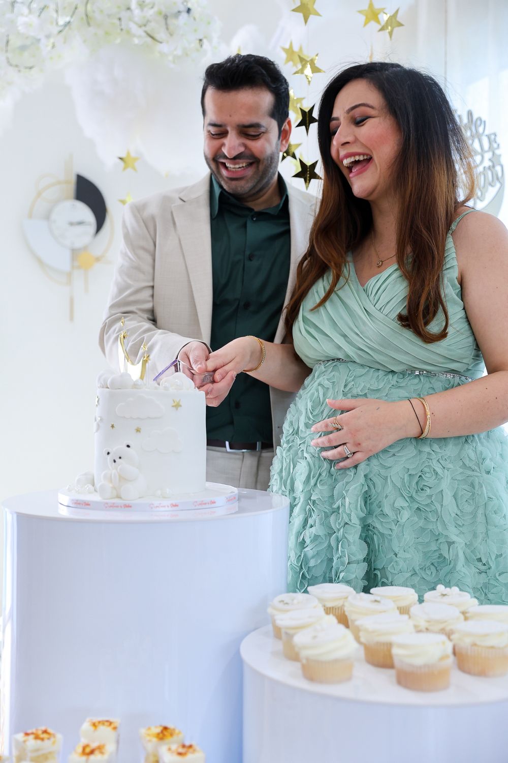 A couple shares a joyful moment while cutting cake at a celebration with star decorations.