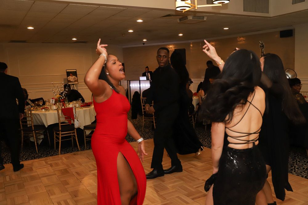 Guests dance and celebrate on a wooden dance floor at an indoor event.