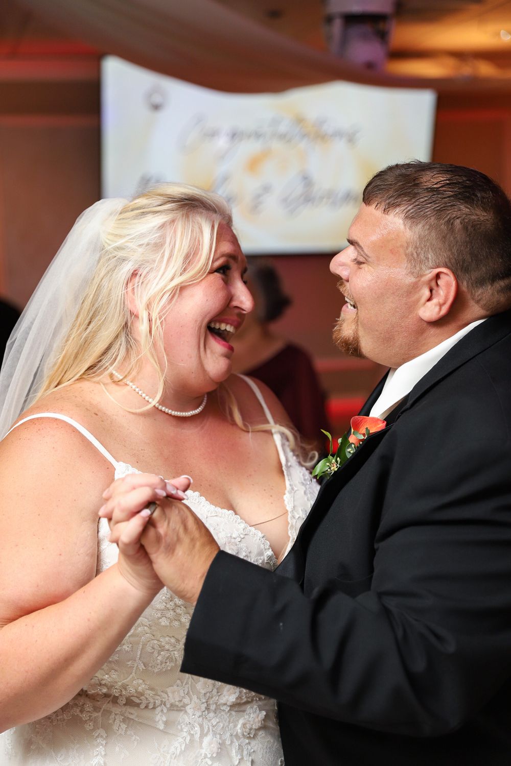 A joyful couple shares a tender laughing moment while dancing at their wedding reception.