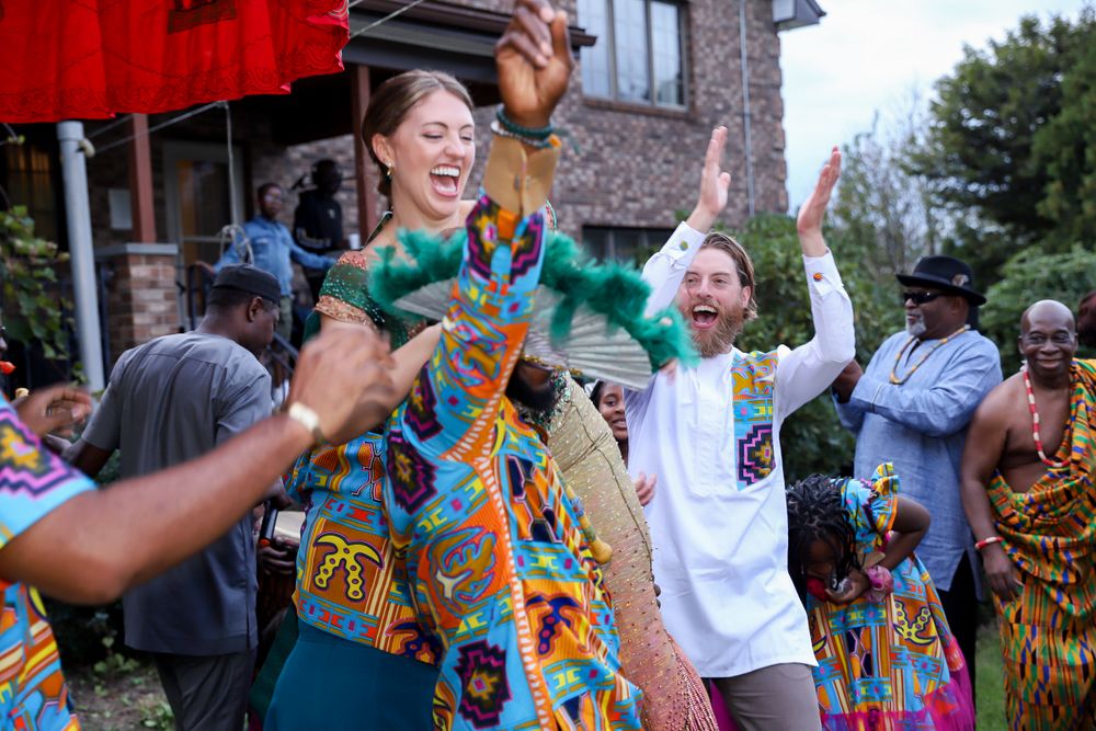 Energetic dancers celebrate during an outdoor festival with colorful clothing and joyful movements.