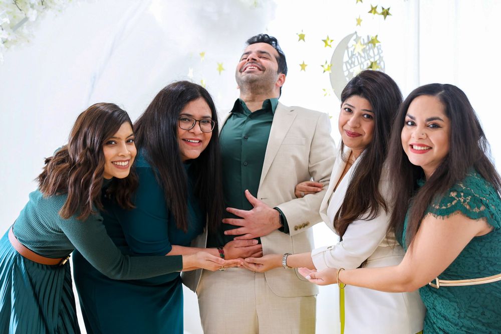 A group poses together in coordinated teal and green outfits at a celebration.