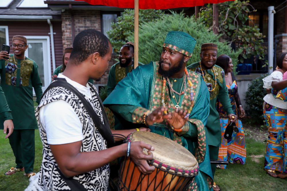 Two musicians play drums together during a cultural performance outdoors.