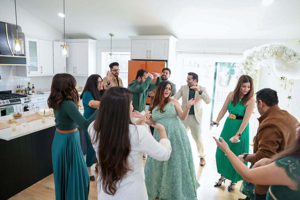 Guests in turquoise dresses celebrate together in a modern white kitchen.