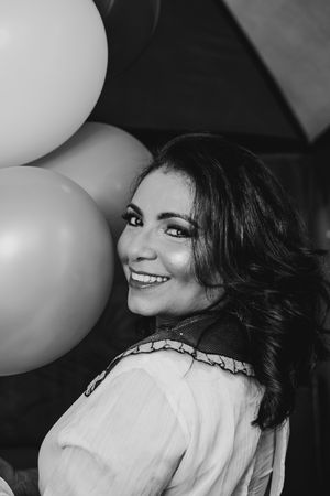 Black and white portrait with white balloons capturing joyful celebratory moment.