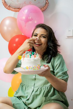 Birthday celebration with colorful balloons and white cake with sprinkles in mint green setting.