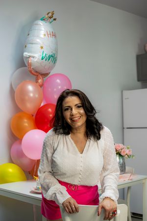 Celebratory scene with pink and peach balloons, white blouse, and bright fuchsia skirt.
