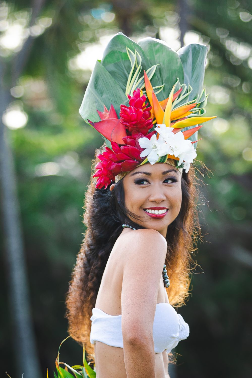 Traditional Hawaiian dancer wearing tropical flower headdress and white outfit.