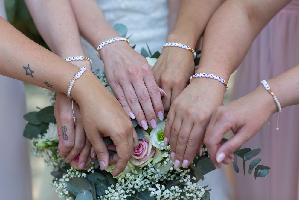 Close-up of hands wearing matching bracelets with floral decorations.