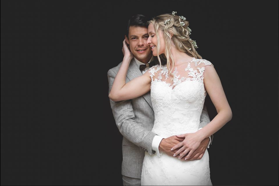 Romantic wedding portrait showing tender embrace against dark background.