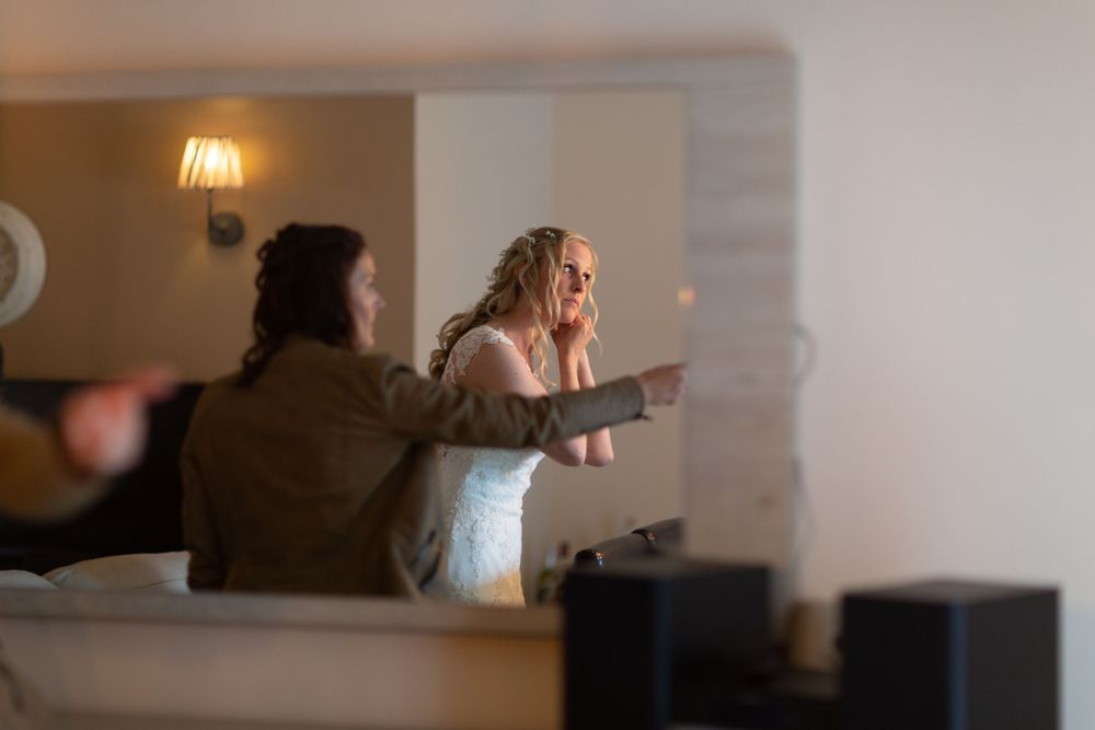 Candid moment captured through window during wedding preparations.