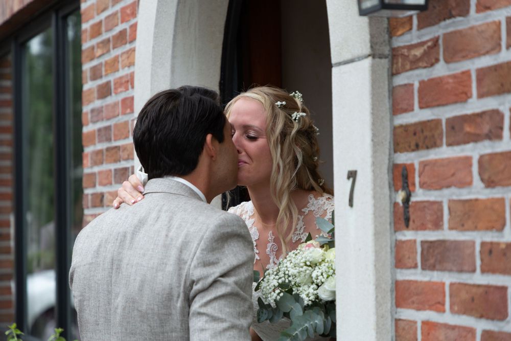 Intimate wedding moment captured near brick doorway with white bouquet.