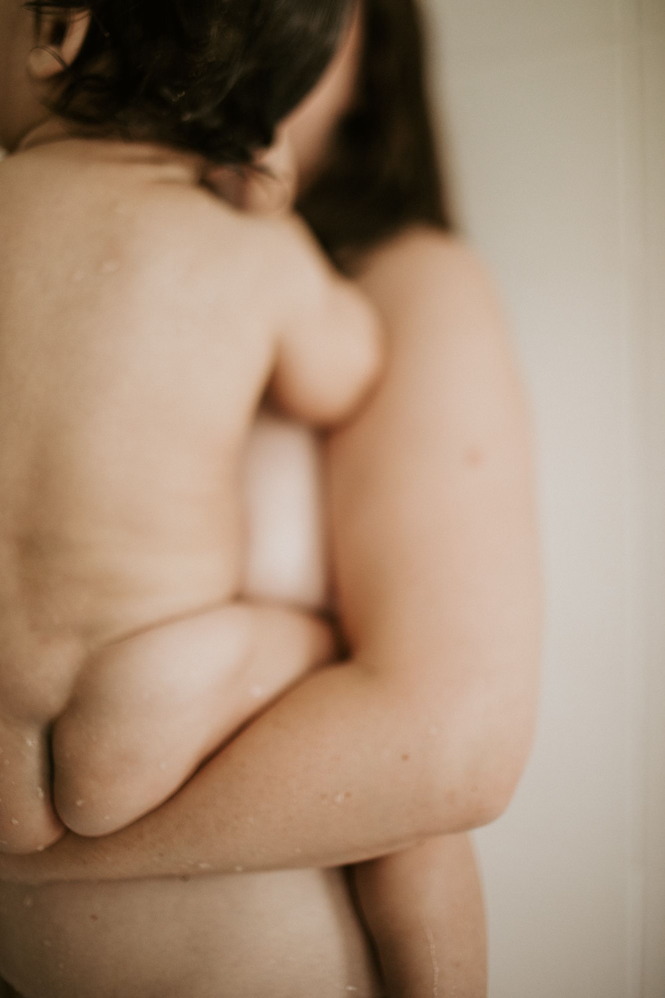 Close-up black and white photo of a woman's bare back with arms crossed in soft focus.
