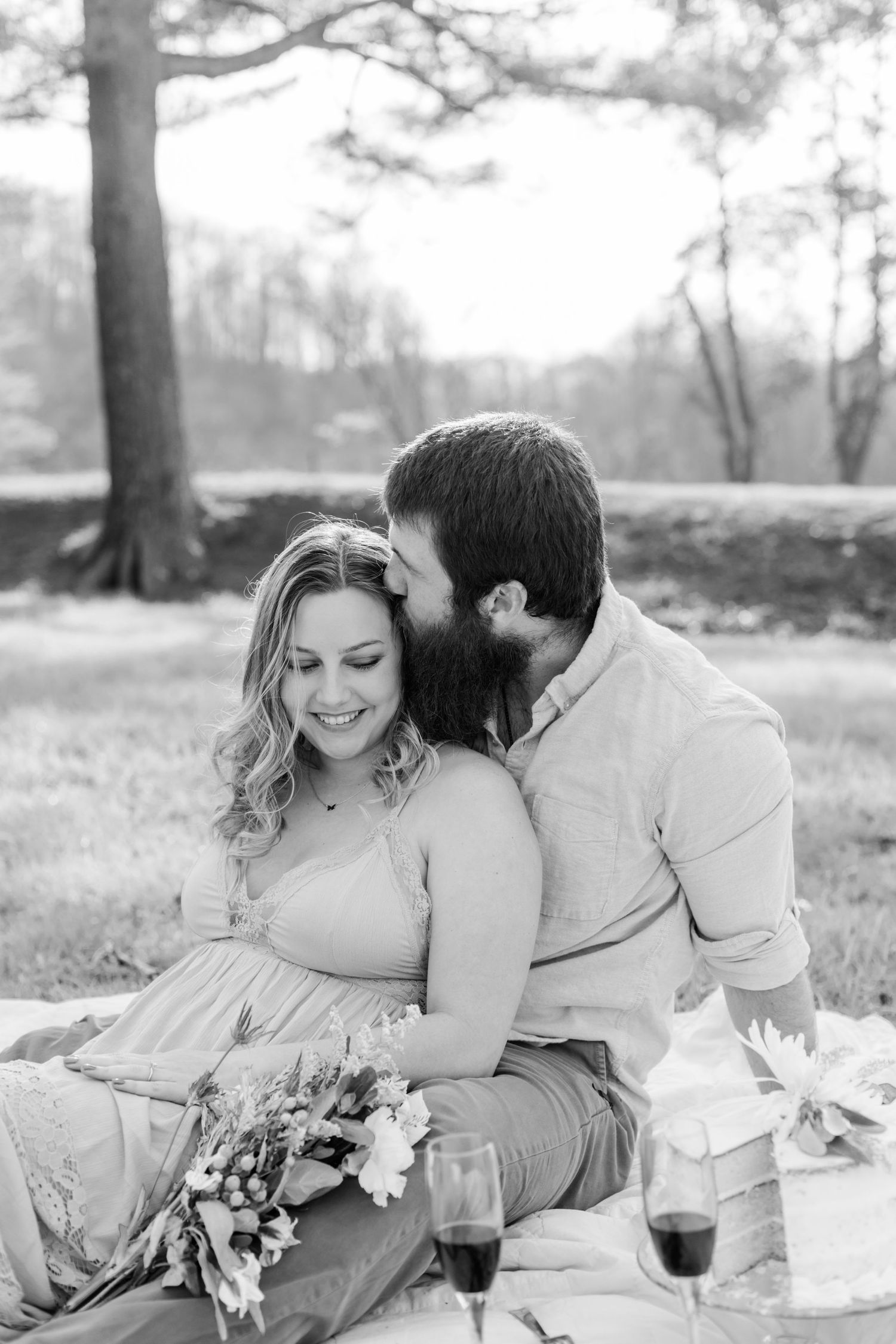 Black and white photo of a romantic outdoor picnic with flowers and blankets.
