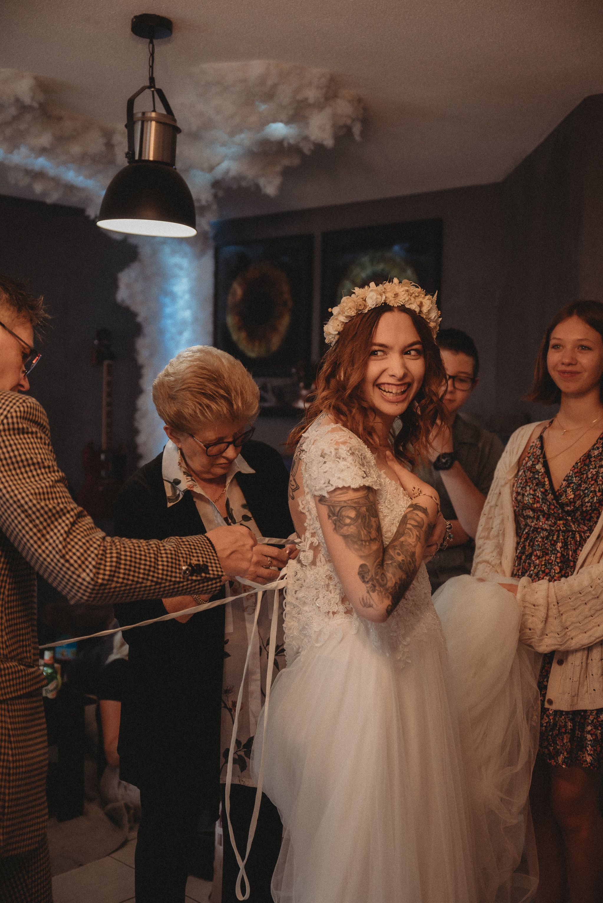 A joyful moment during wedding dress preparations with attendees helping with final adjustments.