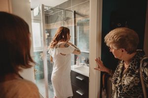 Wedding preparations in a modern bathroom with multiple people getting ready.
