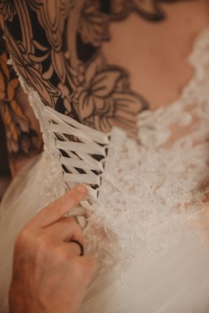 Close-up detail of the corset-style lacing on the back of an ornate white wedding dress.