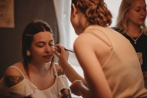 A makeup application session in progress with warm lighting and artistic composition.