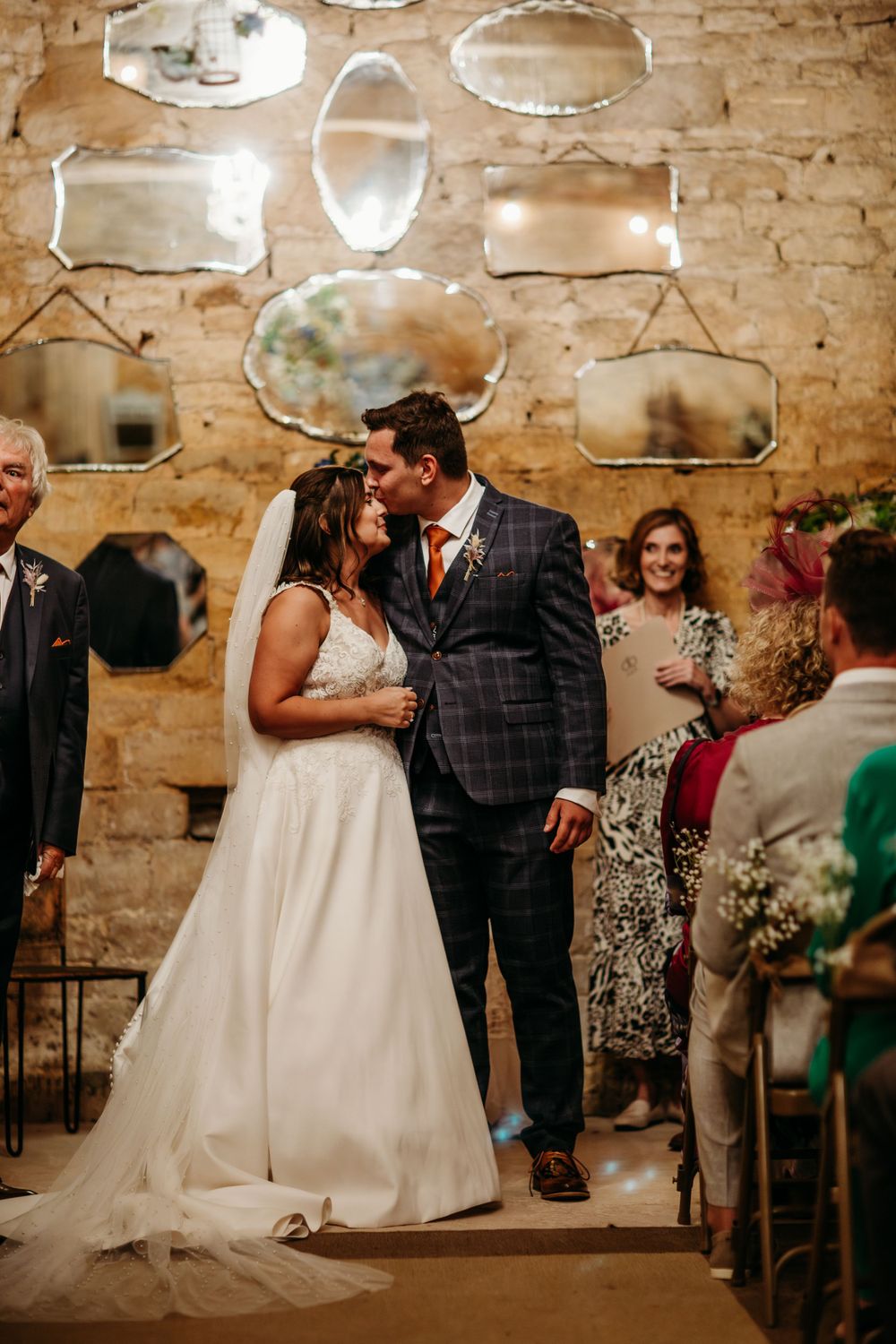 Intimate wedding moment in a vintage stone-walled venue decorated with antique mirrors.