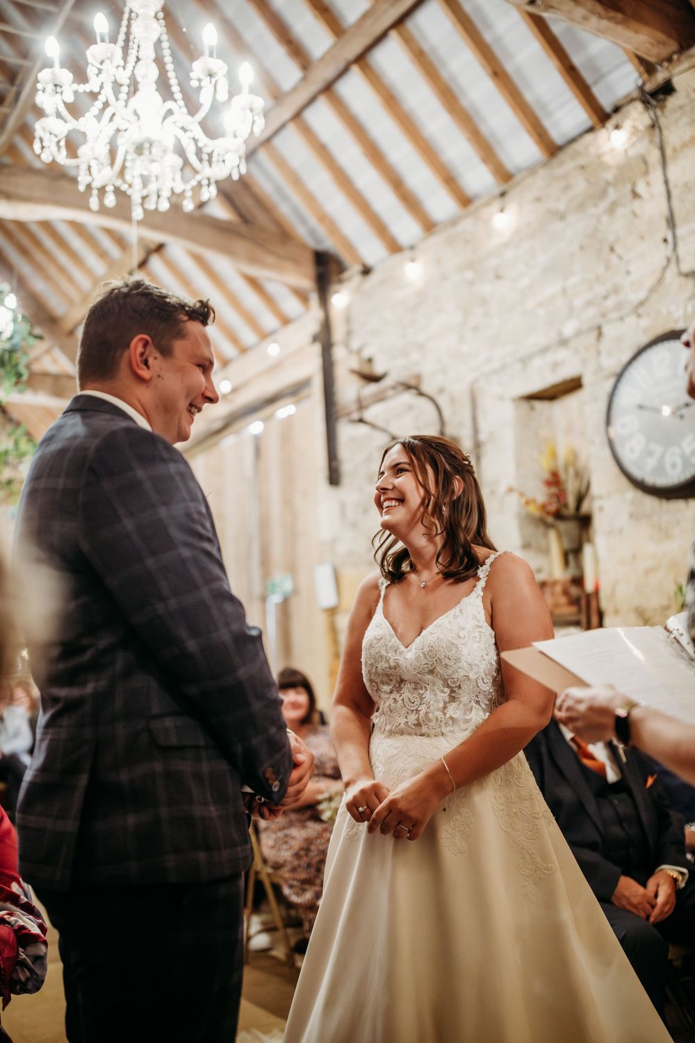 A joyous wedding ceremony in a rustic barn venue with exposed beams and elegant chandeliers.