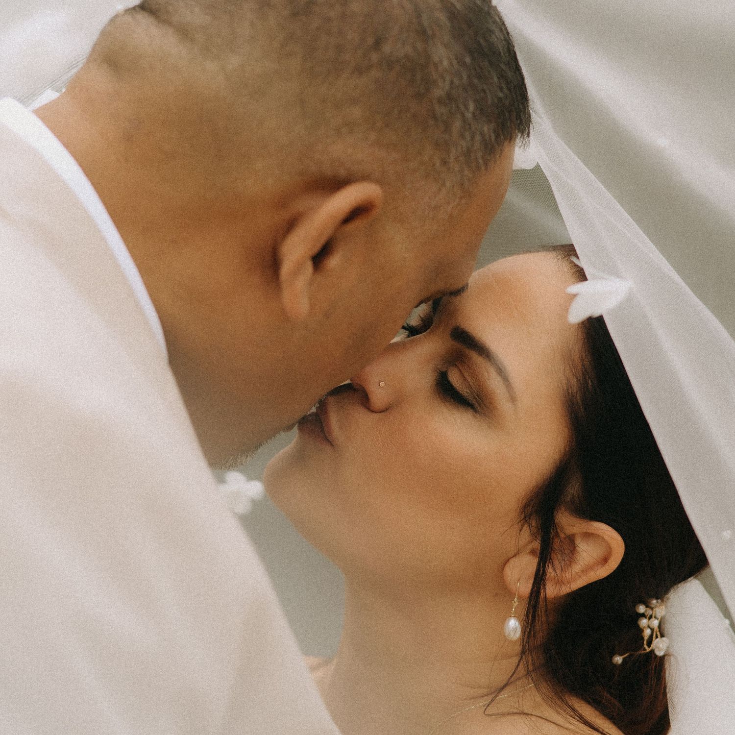 A romantic close-up portrait captures an intimate wedding moment in soft lighting.