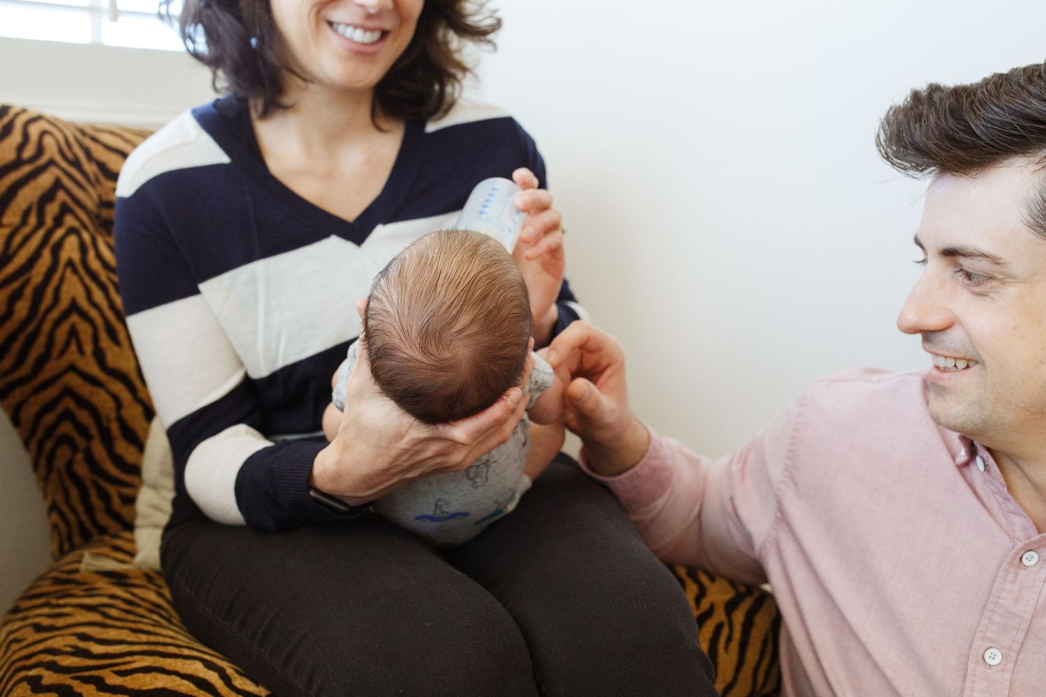 Everett newborn photographer: A mother holds her newborn while dad look on at an in-home newborn photography session