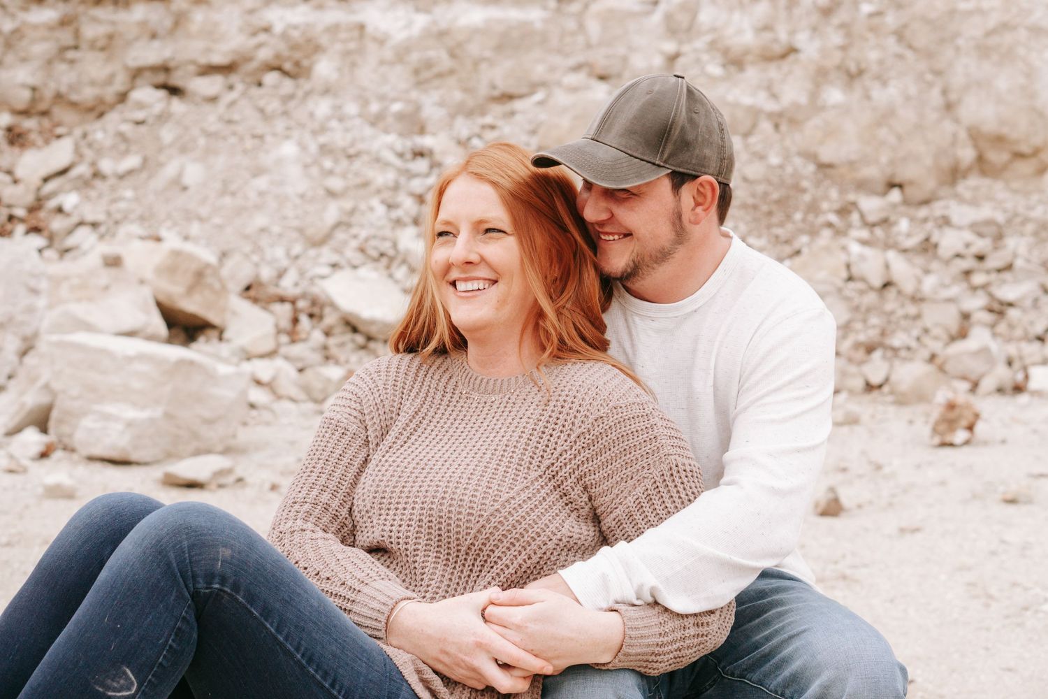 Couple sitting casually together on rocky terrain.