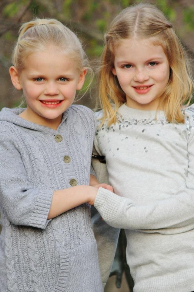 Children wearing matching winter sweaters pose together outdoors.