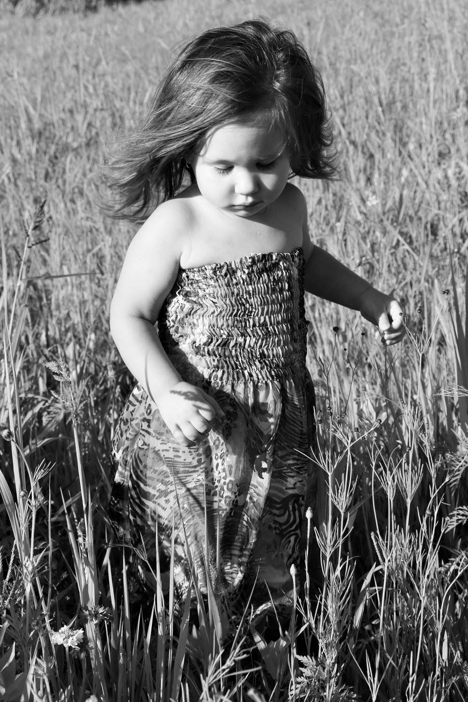 Black and white portrait in a wheat field wearing a patterned dress.