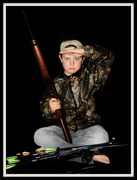 Person in camouflage clothing holding hunting equipment in dark lighting conditions.