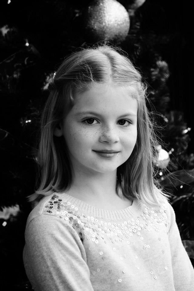 Black and white holiday portrait with a decorated Christmas tree in background.