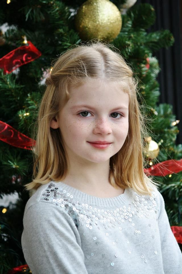 Holiday portrait in front of a Christmas tree with gold ornaments and red ribbons.