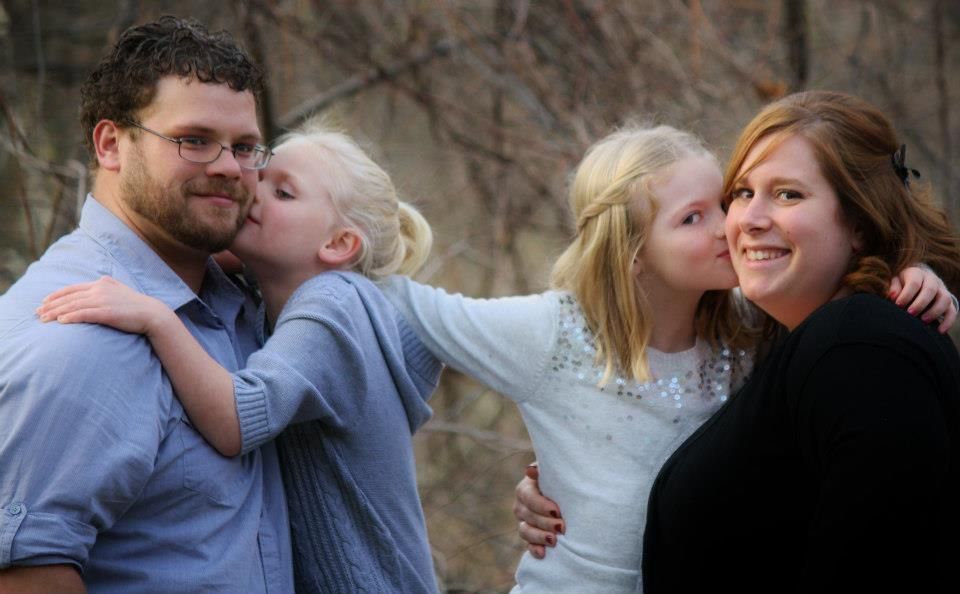 Candid family moment of affection and laughter outdoors.