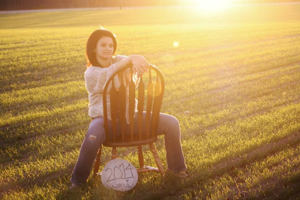 A casual outdoor portrait with a wooden chair and volleyball at sunset.