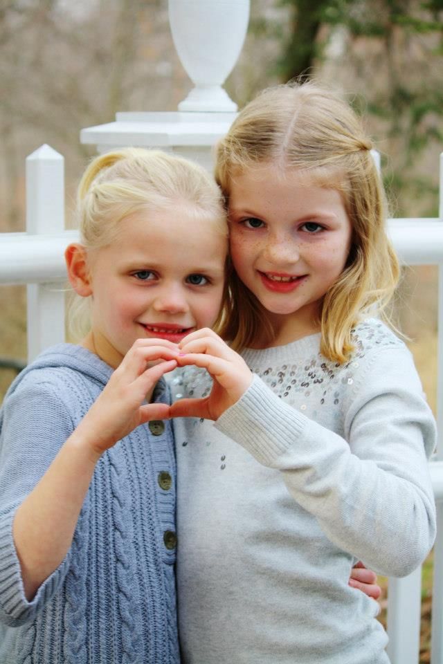 Two children in winter sweaters giggle and share secrets.